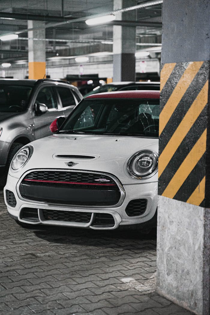 A white Mini Cooper parked in a dimly lit urban underground garage.